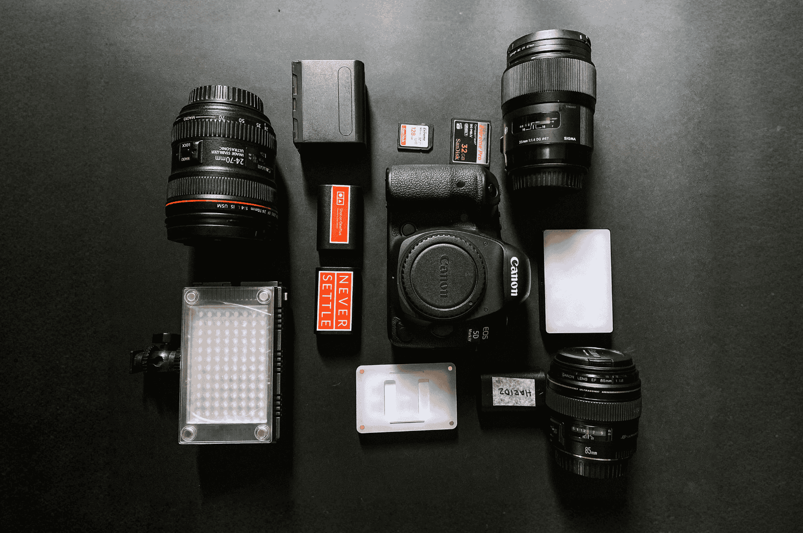 Night-And-Day- (3) Flat lay of Canon DSLR gear and accessories arranged on a dark surface—evoking the technical precision behind both natural and artificial lighting setups in food photography. The mix of prime and zoom lenses, SD cards, and white balance tools reflects the photographer’s readiness to adapt from sunlit shoots to moody, low-light compositions.