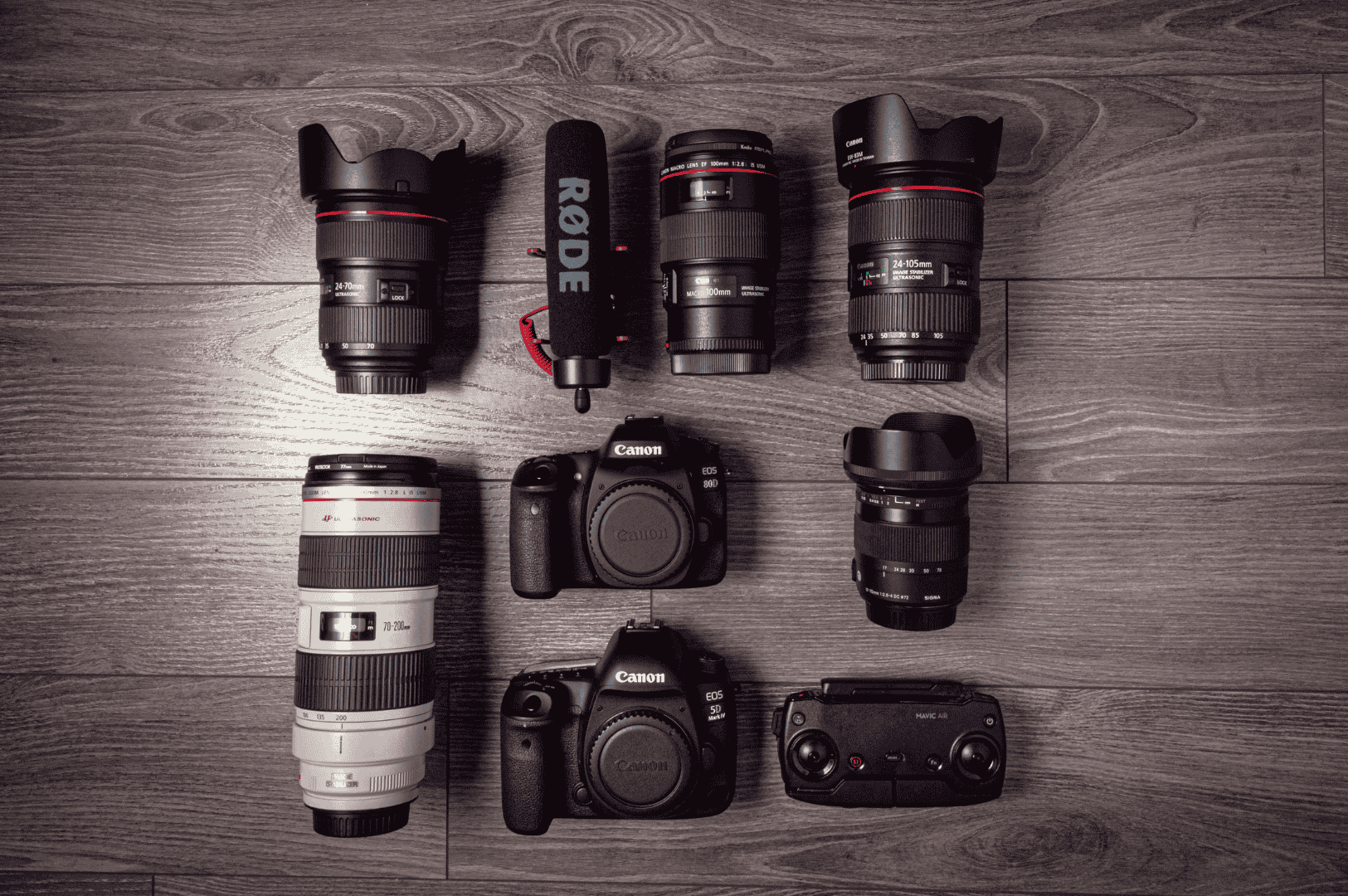 Night-And-Day- (6) Flat lay of professional Canon camera gear, RØDE microphone, and control accessories arranged on a wooden floor—symbolizing the technical backbone of food photography across lighting extremes. The diverse lenses and dual DSLR bodies suggest readiness for both crisp daylight compositions and moody, low-light captures, bridging still and motion storytelling.
