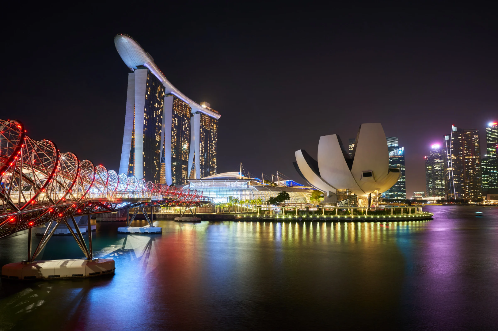 Best-Dining-1 Nighttime view of Marina Bay in Singapore featuring the illuminated Helix Bridge, Marina Bay Sands hotel, and ArtScience Museum, symbolizing the city's vibrant culinary and architectural scene.