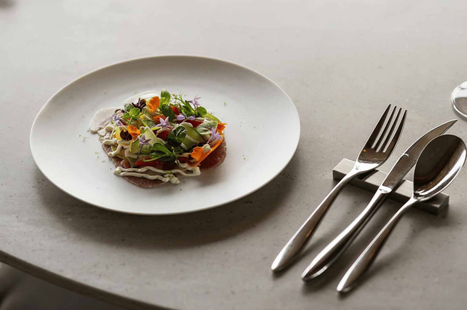 Best-Resto-SG- (2) A refined salad of vibrant greens, edible flowers, and delicate sauces plated with precision—an elegant preview of Singapore’s top-tier dining artistry.