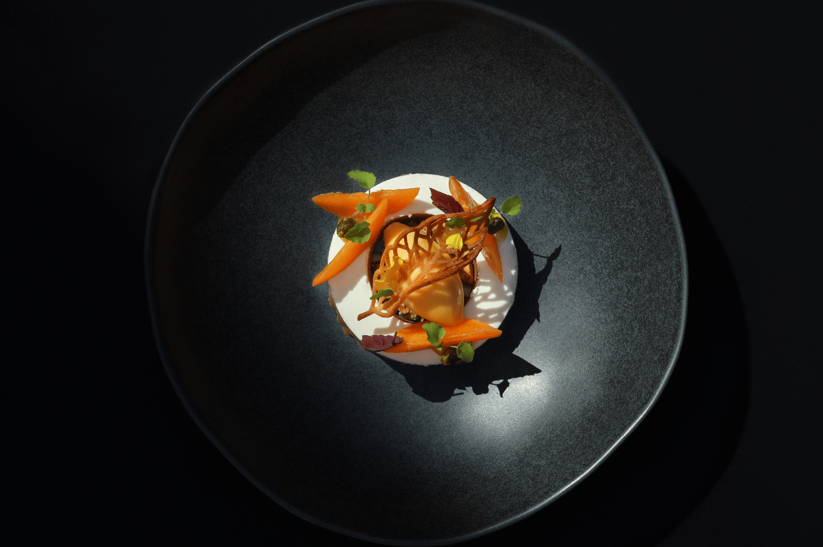 Michelin-Guide-SG- (4) Vibrant plated dessert with orange quenelle, microgreens, and lattice garnish, showcasing the precision and artistry of Singapore’s Michelin-starred culinary documentation.