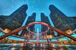 Low-angle view of the Fountain of Wealth in Suntec City, Singapore, illuminated at night with tall skyscrapers towering in the background.