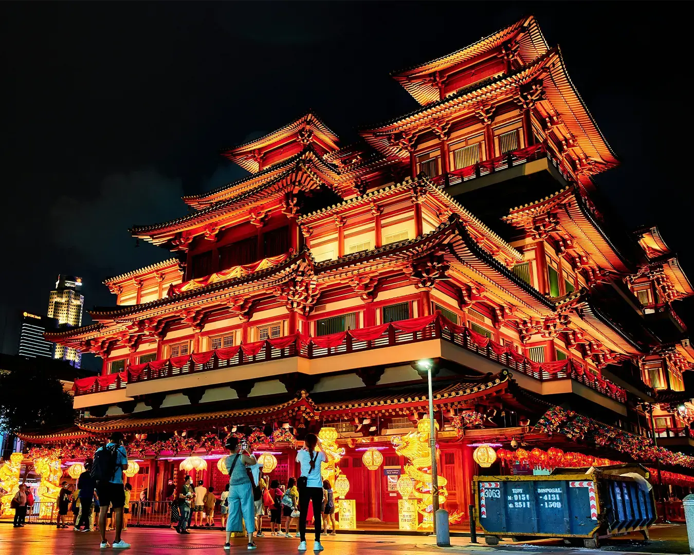 The ornate red-and-gold exterior of the Buddha Tooth Relic Temple rising above Chinatown, featuring traditional Chinese architecture, intricate carvings, and tiered rooftops.