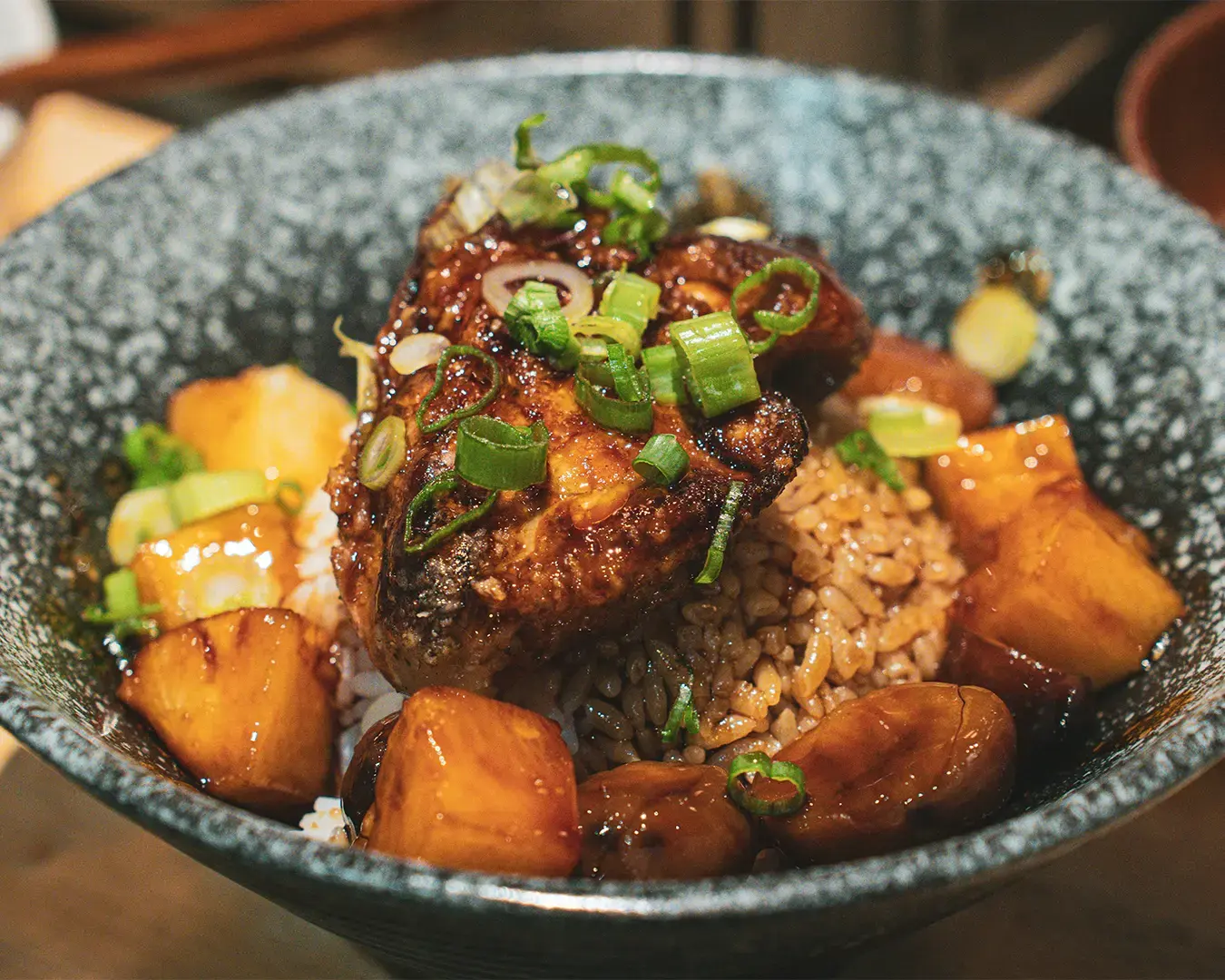 A close-up of a Japanese rice bowl topped with neatly arranged ingredients, showcasing the glossy grains of rice and carefully prepared toppings in a clean and minimal presentation.