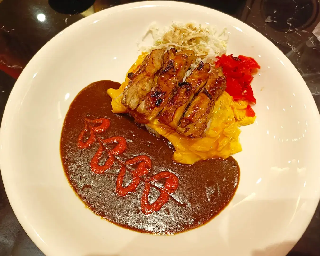 Grilled chicken on creamy omelette, drizzled with rich brown sauce, garnished with shredded cabbage and red pickle. Vibrant and appetizing.