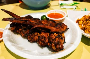 Chicken wings stacked on one another with lime and sauce on a white plate.
