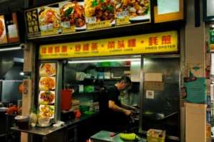 Bedok North Fried Oyster during night with busy staff cooking meals under their yellow logo signage and printed menu items.