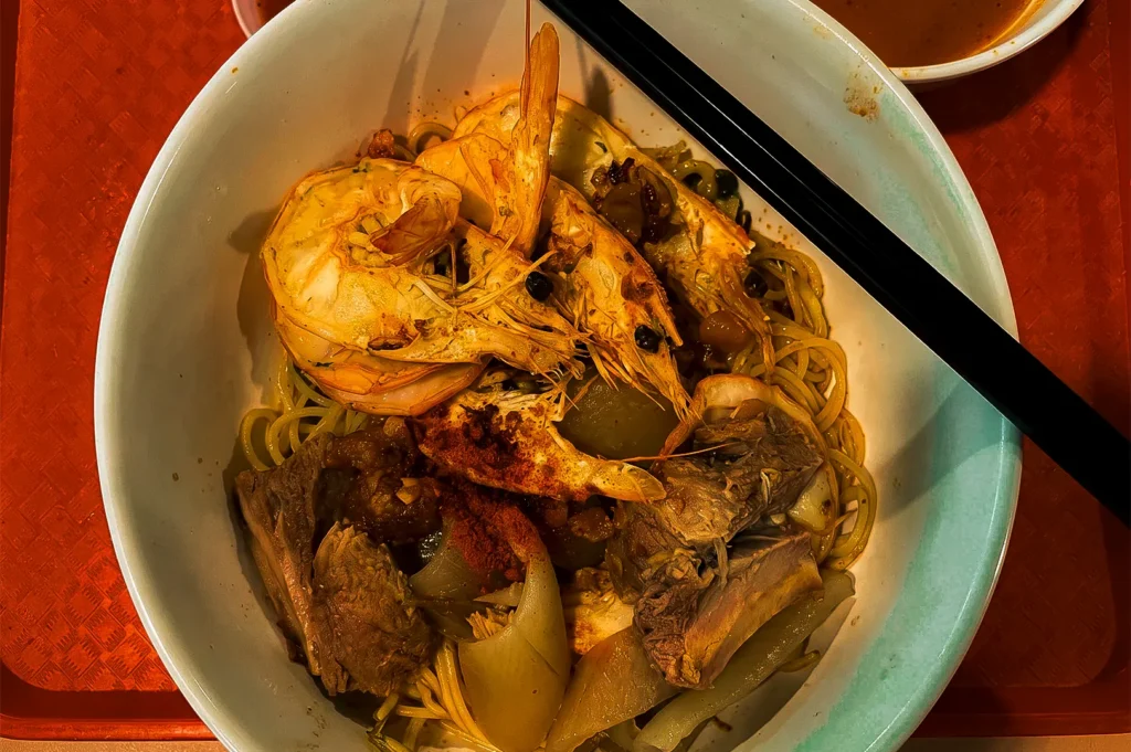 A serving of a prawn noodles in a white bowl served at ONE.85 Big Prawn Mee.