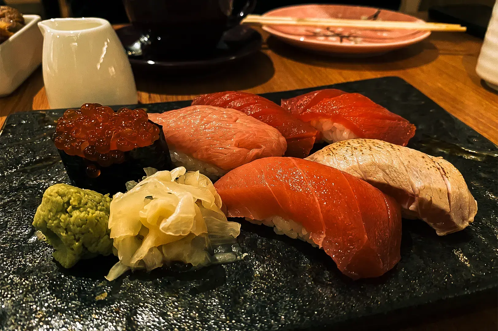 A closer view of the different sashimi dishes on a black serving plate available at Issho Izakaya.