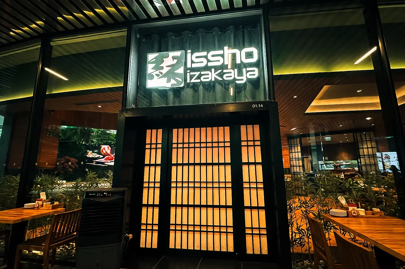 Issho Izakaya exterior with the logo signage on top of a traditional Japanese style entrance door with glass wall panels .