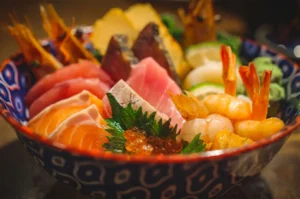 A close up view of a chirashi don bowl with fresh sashimi of different flavors and colors inside.